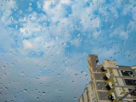 glas regen druppels, flat gebouwen, bewolkt, blauw lucht, weer voorspelling, meteorologisch afdeling foto