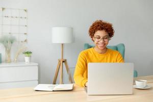 Afrikaanse Amerikaans meisje gebruik makend van laptop Bij huis kantoor op zoek Bij scherm typen chatten lezing schrijven e-mail. jong vrouw hebben virtueel vergadering online babbelen video telefoontje conferentie werk aan het leren van huis foto