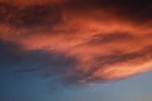 dramatisch zonsonderganglandschap met gezwollen wolken verlicht door oranje ondergaande zon en blauwe lucht. foto