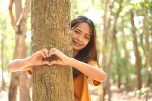 concept van besparing de wereld Aziatisch vrouw knuffelen een boom foto