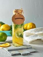 limonade met citroenen, munt bladeren, limoen in een glas fles foto