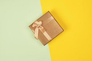 Gesloten gouden geschenk doos met een boog Aan een groen geel achtergrond foto