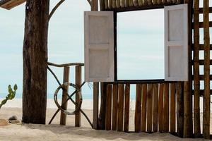 houten venster kader door de sae in zonnig dag zomer, strand hut Aan zand strand met venster Open door zee visie, kust visie punt voor zomer vakantie promoten of Product presentatie foto