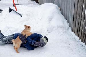 puppy's gooide de kind Aan de sneeuw en iedereen verheugt zich. grappig spellen met een hond buiten in winter foto