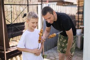 grappig vader en zoon proberen gegrild vlees foto