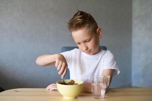 schattig jongen eet een droog ontbijt Bij huis en glimlacht foto
