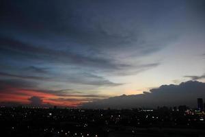 zonsondergang donker blauw wolk met wit gouden licht lucht achtergrond en stad licht middernacht avond tijd foto