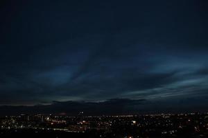 donker blauw wolk met wit licht lucht achtergrond en stad licht middernacht avond tijd foto