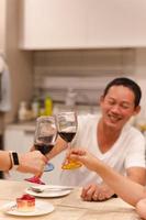Aziatisch Mens hebben een viering met vrienden roosteren glas van rood Bij avondeten feest. foto