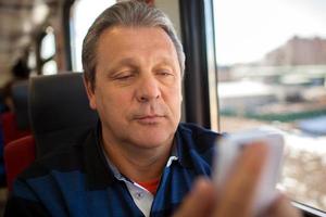 man met behulp van mobiele telefoon tijdens een treinrit foto