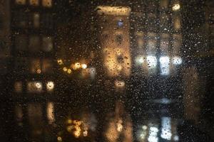 regen druppels Aan glas venster Bij nacht foto