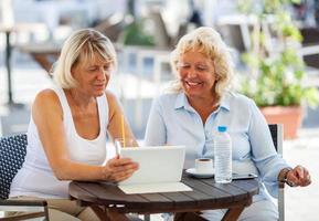 twee volwassen vrouwen die een tablet gebruiken foto