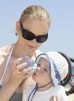 moeder die haar zoon voedt op het strand foto