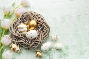 nest met Pasen eieren geschilderd gouden kleuren Aan een groen houten achtergrond. foto