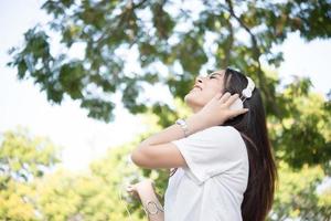 portret van een lachend meisje met koptelefoon luisteren naar muziek in de natuur foto