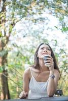 jonge vrouw met wegwerp koffiekopje zittend buiten