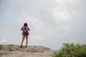 wandelaar met rugzak staande op de top van een berg en genietend van uitzicht op de natuur foto