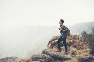 jonge hipster wandelaar met rugzak zittend op de top van de berg