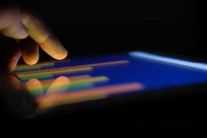 man's hand bezig met digitale tablet op kantoor, met behulp van zelfgemaakte grafiek in het donker