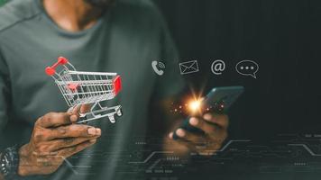 Mens Holding boodschappen doen kar en gebruik makend van smartphone Bij huis kantoor, zakenman boodschappen doen online, e-commerce, internet bankieren, uitgeven geld, werken van huis concept, Aziatisch Mens. foto