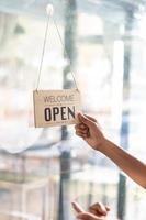 koffie winkel medewerkers zijn flippen op te slaan opening teken geïnstalleerd Aan glas voorkant deur zo dat klanten kan zien op te slaan opening teken en gebruik de onderhoud binnen de koffie winkel. opstarten bedrijf concept. foto