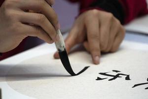 Japans vrouw schrijven naam Charles in ideogrammen met borstel foto