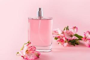 mooi fles van kunstmatig verstuiven of parfum Aan een roze achtergrond met astromerie bloemen. voorkant visie. aroma presentatie. sjabloon, Product indeling. foto
