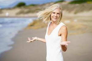 gelukkige volwassen vrouw die op het strand loopt, haar vrije tijd doorbrengt, geniet van haar vrije tijd foto