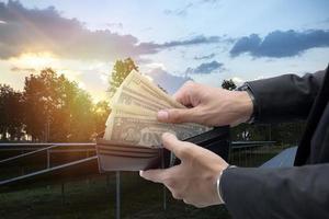 hand- Holding dollar rekeningen dat kijken uit van een portemonnee Aan een achtergrond van zonne- panelen. bespaart geld. gebruik makend van zonne- energie. groen elektriciteit. foto