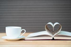 bladzijde van boek gebogen hart vorm en koffie kop foto