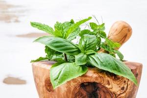 groene kruiden in een houten vijzel foto