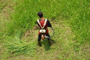 top visie van een Mens in een gewaad gras maaien de gras met een trimmer foto