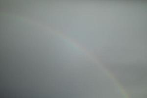regenboog in lucht. flauw gloed van regenboog. grijs lucht en helder strepen. foto