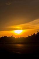 de groot zon is over naar reeks in de avond net zo de lucht is een warm en beangstigend geel oranje, iets natuur heeft gemaakt in landelijk Thailand. foto