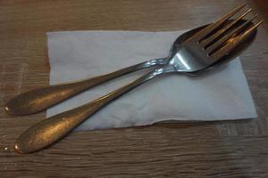 vork met lepel en zakdoek papier Aan een houten tafel in een cafe. foto