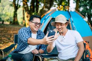 portret gelukkig Aziatisch Mens vrienden maken een video telefoontje met smartphone in camping foto