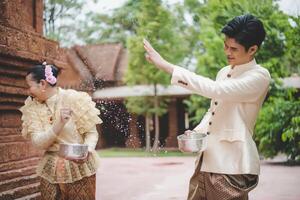 jong paar spatten water van kom Aan songkran festival foto