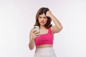 portret van verward jong vrouw gebruik makend van mobiel telefoon geïsoleerd over- wit achtergrond foto
