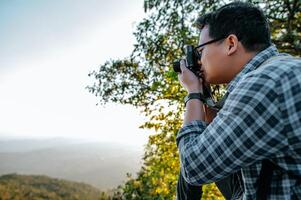 jong backpacker Mens gebruik camera naar nemen afbeeldingen in Woud. foto