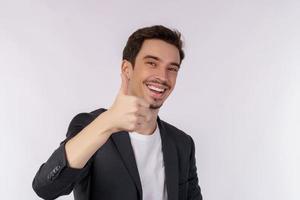 portret van gelukkig glimlachen jong zakenman tonen duimen omhoog gebaar en op zoek Bij camera Aan geïsoleerd over- wit achtergrond foto
