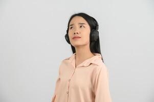 portret van jong Aziatisch vrouw genieten van luisteren naar muziek- met groot hoofdtelefoons in studio geïsoleerd Aan wit achtergrond foto
