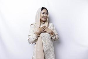 gelukkig bedachtzaam dankbaar jong Aziatisch moslim vrouw met haar hand- Aan haar borst glimlachen geïsoleerd Aan wit achtergrond foto