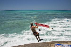 Mens jumping van pier met lichaam surfen foto