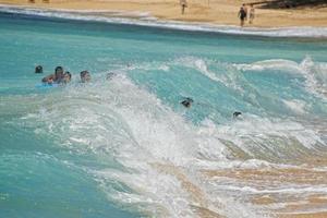 kinderen spelen in zee golven in Hawaii foto