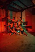 een groep van mannen zonder kleren dansen poses in een oud gebouw met een rood licht foto