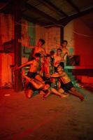 een groep van mannen zonder kleren dansen poses in een oud gebouw met een rood licht foto