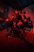 een groep van Aziatisch tieners in zwart kleren poseren heel ondeugend met hun vrienden in een magazijn met een rood licht foto