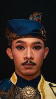 een Aziatisch Mens vervelend een traditioneel Indonesisch dans kostuum is bruin en zijn gezicht is vol van bedenken foto