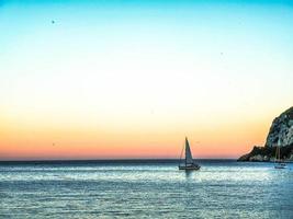 een zeilboot in de blauw zee en met een zomer zonsondergang, in western Ligurië in juli 2022 foto