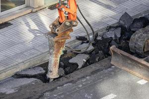 bouw machine breken en boren een loopgraaf in een weg voor repareren foto